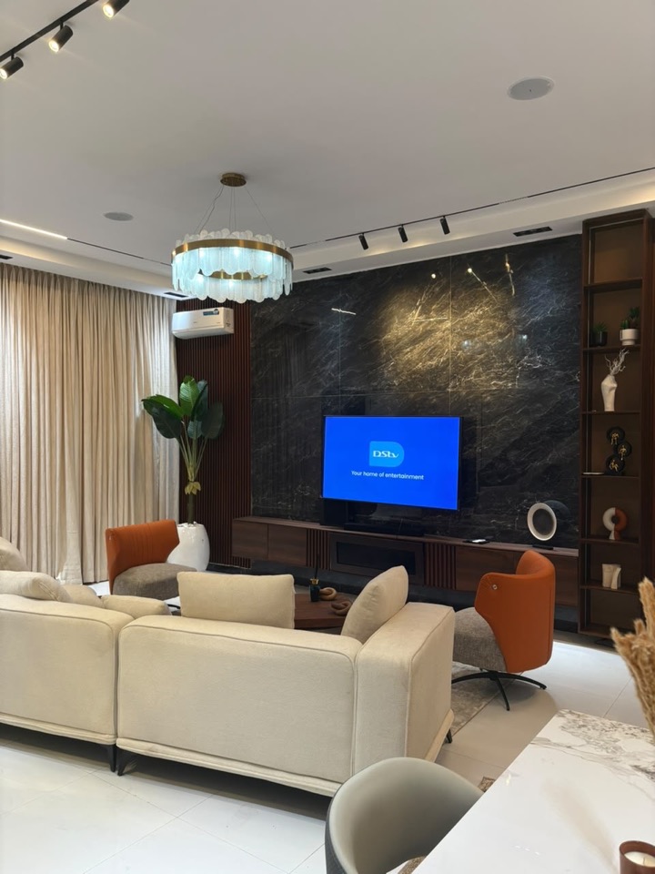 Cream sofas facing a marble wall under a sculptural chandelier