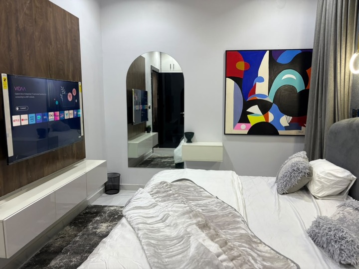 Guest bedroom with abstract artwork, arched mirror and floating console